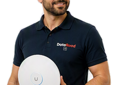 Bearded man in a navy polo shirt holding a round white wireless device with a blue ring and a 'U' button, wearing a DotaRoad logo polo.