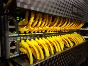 réseaux-informatiques-1024x768 - DataRoad Une rangée de commutateurs réseau Cisco auxquels sont raccordés de nombreux câbles Ethernet jaunes.