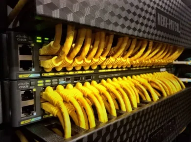 Row of Cisco network switches with numerous yellow Ethernet cables connected.